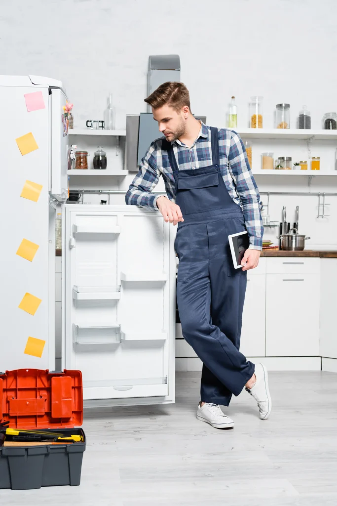 Appliance repairman inspecting refrigerator cooling system.