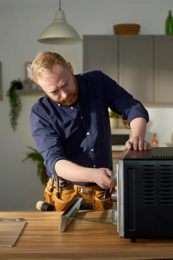 Microwave technician replacing turntable motor during home service.